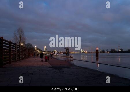 Panorama all'aperto dell'area allagata lungo la passeggiata lungo il fiume Reno e ponte sospeso durante la sera con tramonto e cielo crepuscolo. Foto Stock