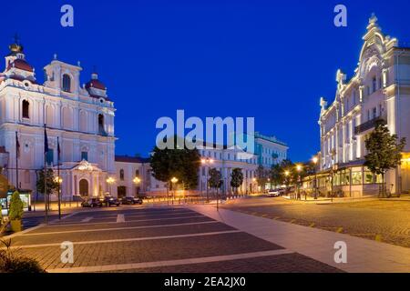 Vista notturna della chiesa illuminata di San Casimiro e Astorija hotel nel centro storico di Vilnius, Lituania Foto Stock