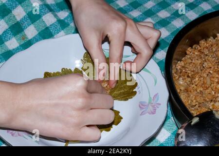La donna sta avvolgendo foglie di uva per il Sarma turco o Dolma (Yaprak Sarma). Tradizionale cucina turca. Concetto di cucina casalinga. Foto Stock