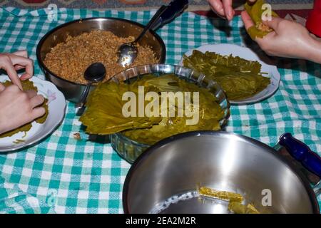 La donna sta avvolgendo foglie di uva per il Sarma turco o Dolma (Yaprak Sarma). Tradizionale cucina turca. Concetto di cucina casalinga. Foto Stock