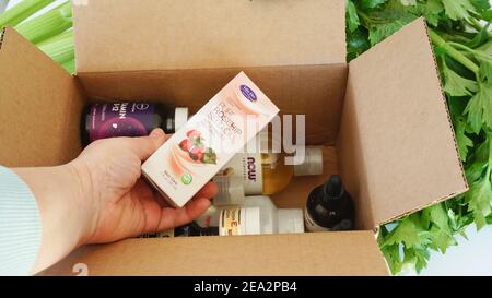 Alicante, Spagna - Gennaio, 2021: Sito web IHerb supplementi e bellezza prodotti naturali scatola disimballaggio. Donna caucasica mano che tiene olio di rosa anca Foto Stock