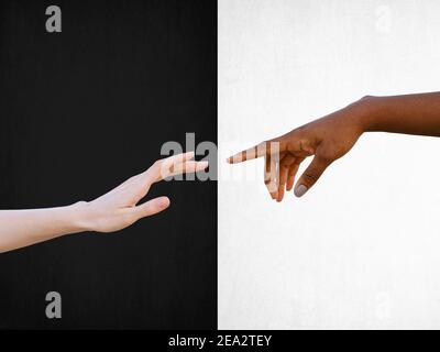 Concetto di amicizia e rispetto razziale con mani bianche e nere avvicinandosi l'uno all'altro su sfondo bianco e nero Foto Stock
