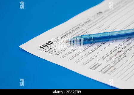 Chiusura della dichiarazione dei redditi su sfondo blu. Penna blu sul modulo fiscale 1040. Messa a fuoco selettiva Foto Stock