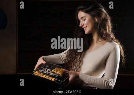 Sushi in scatola cibo sano consegna online servizio. La ragazza tiene in mano 2 set di sushi. Cucina giapponese: Panini, salsa di soia, wasabi Foto Stock