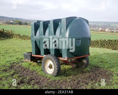 Grande serbatoio dell'acqua in plastica di forma verde su rimorchio a due ruote in campo agricolo Foto Stock