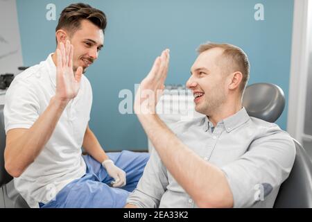Felice paziente maschile dando cinque al dentista Foto Stock