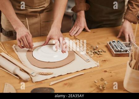 Primo piano di artigiani maschili irriconoscibili che fanno ceramica in laboratorio di ceramica, copisteria Foto Stock