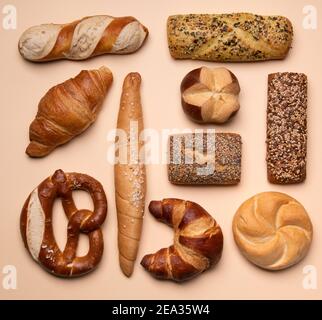 Diversi tipi di pasticceria concetto piatto. Su sfondo crema. Danese, croissant, pane pretzel. Foto Stock