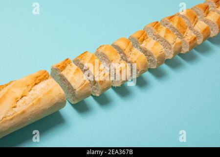 Baguette tagliata su sfondo blu. Concetto di pane semplice Foto Stock