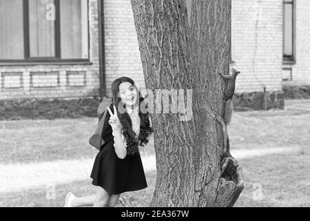 Appassionato di Zoologia. Felice bambino mostra segno di pace. Scoiattolo rosso salire tronco albero. Scienza animale. Zoologia. Ritorno a scuola. Educazione alla scienza naturale. Diventare zoologo è nel suo futuro. Foto Stock