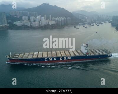 Vista aerea da un drone di una nave container, che trasporta container di grandi dimensioni attraverso una delle più trafficate rotte di navigazione dell'Asia - il canale di Lamma - tra Aberdeen sull'isola di Hong Kong e l'isola di Lamma. Il percorso è così affollato che ogni nave richiede una barca pilota da e per le banchine per navigare in questa parte del mare. © Olli Geibel Foto Stock