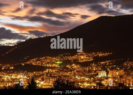 Paesaggio notturno aereo della città di Quito al tramonto con il vulcano Pichincha sullo sfondo, Ecuador.