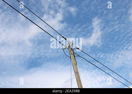 Vecchio palo di potenza in legno con linee di alimentazione contro blu nuvoloso cielo Foto Stock