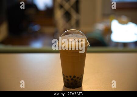 Tè al latte tailandese con zucchero di canna e tapioca su sfondo sfocato. Foto Stock