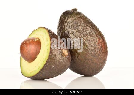 Un intero e mezzo, verde scuro, gustoso avocado organico maturo su sfondo bianco. Foto Stock