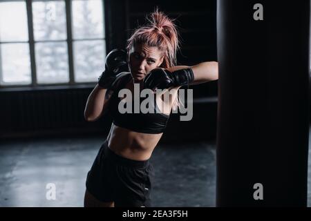 fighter femminile cool in guanti da boxe si allena in palestra. Arti marziali miste Foto Stock