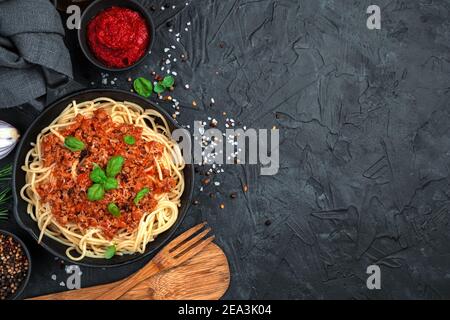 Deliziosa pasta bolognese con formaggio e basilico su fondo nero di cemento. Foto Stock