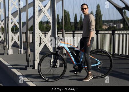 bel giovane con ebike e sfondo urbano . Foto Stock