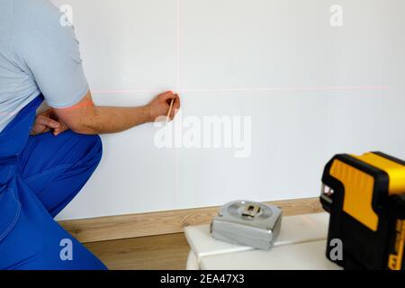 Uno specialista contrassegna i punti su una parete con un'elettronica laser per l'indicazione di livelle e linee a piombo Foto Stock