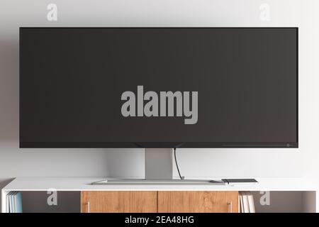 TV widescreen sul piedistallo TV in un moderno salotto con parete bianca. Vista frontale Foto Stock
