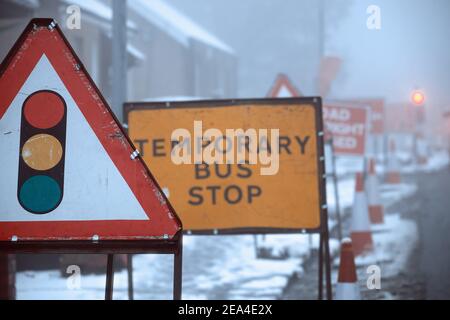 Indicazioni stradali sulla strada invernale. Indicazioni stradali e fermata temporanea degli autobus. Scozia, Regno Unito Foto Stock