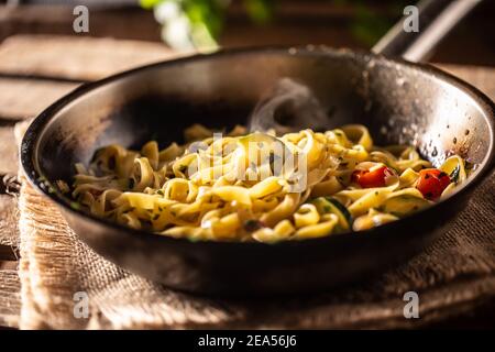 Tagliatelle vegetariane con zucchine e pomodori serviti in padella calda e frizzante. Foto Stock
