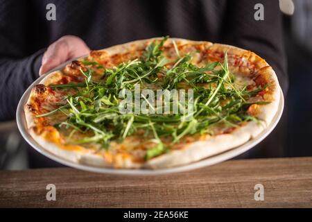 Pizza italiana appena fatta con salsa di pomodoro e rucola. Foto Stock