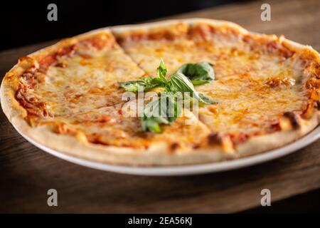 Pizza quattro formaggi con quattro tipi di formaggi, contorni croccanti e basilico fresco sulla parte superiore. Foto Stock