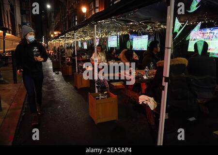 Philadelphia, Stati Uniti. 7 Feb 2021. La gente guarda Super Bowl LV ai tavoli da pranzo all'aperto separati da tende di plastica al Trademan's, un bar e ristorante, a Philadelphia, USA. Credit: Chase Sutton/Alamy Live News Foto Stock