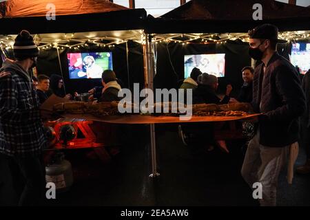 Philadelphia, Stati Uniti. 7 Feb 2021. Una cheesesteak Philly lunga cinque piedi viene portata a un tavolo da pranzo all'aperto al Tradeesman's, un bar e ristorante, con Super Bowl LV che gioca alla televisione a Philadelphia, USA. Credit: Chase Sutton/Alamy Live News Foto Stock