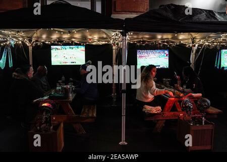 Philadelphia, Stati Uniti. 7 Feb 2021. La gente guarda il lancio del Super Bowl LV su tavoli da pranzo all'aperto separati da tende di plastica al Trademan's, un bar e ristorante, a Philadelphia, USA. Credit: Chase Sutton/Alamy Live News Foto Stock