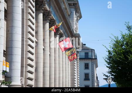 GINEVRA, SVIZZERA - 19 GIUGNO 2017: Bandiere di Ginevra e della Svizzera che rinunciano al vento davanti all'Hotel des Postes, l'ufficio postale principale della p Foto Stock