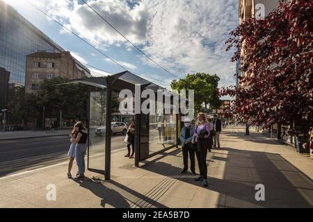 BELGRADO, SERBIA - 23 MAGGIO 2020: Folla di persone, giovani e anziani, uomini e donne, in attesa di un autobus ad una fermata a Belgrado indossare maschera di protezione equi Foto Stock