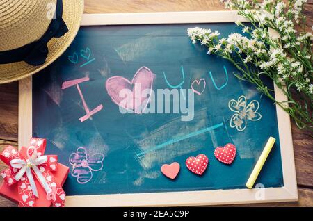 Lavagna con parole scritte in shock che il 'ti AMO' e un cuore floreale è stato posto accanto al bordo - il concetto di San Valentino. Foto Stock