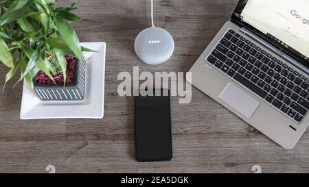 Adelaide, Australia - 7 luglio 2019: Google Home Mini con computer portatile HP con Windows 10 e telefono cellulare impostato sul tavolo accanto l'uno all'altro Foto Stock