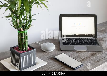 Adelaide, Australia - 7 luglio 2019: Google Home Mini con computer portatile HP con Windows 10 e telefono cellulare impostato sul tavolo accanto l'uno all'altro Foto Stock