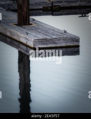 Il molo della barca riflette in acque calme Foto Stock