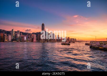 Skyline della città di Hong Kong al tramonto vista dal porto di Hong Kong. Foto Stock