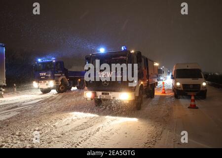 Gera, Germania. 8 febbraio 2021. I membri dell'Agenzia federale tedesca per il soccorso tecnico (THW) stanno assistendo i conducenti di autocarri bloccati nel traffico sull'autostrada 4 vicino a Gera. Dopo un'intensa nevicata durante la notte, il traffico in direzione di Erfurt si è fermato su una montagna. Credit: Bodo Schackow/dpa-zentralbild/dpa/Alamy Live News Foto Stock