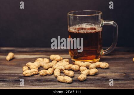 tazza di birra su un tavolo di legno arachidi in conchiglie primo piano su bevande alcoliche Foto Stock