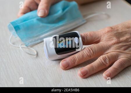 Esame ossimetrico della paziente anziana nella prevenzione della polmonite da Covid 19, esame della donna anziana che usa ossimetro a casa. La donna stessa misura il sangue s Foto Stock