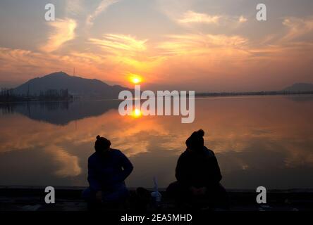 Srinagar, Kashmir controllato dall'India. 7 Feb 2021. La gente siede sulla riva del lago dal durante il tramonto a Srinagar, la capitale estiva del Kashmir controllato dagli Indiani, il 7 febbraio 2021. Credit: Javed Dar/Xinhua/Alamy Live News Foto Stock