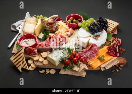 Tavola degli antipasti. Formaggio, fusit e cartone di carne su sfondo scuro. Foto Stock