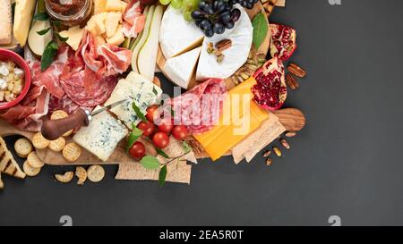 Tavola degli antipasti. Formaggio, fusit e cartone di carne su sfondo scuro. Vista dall'alto, spazio di copia Foto Stock