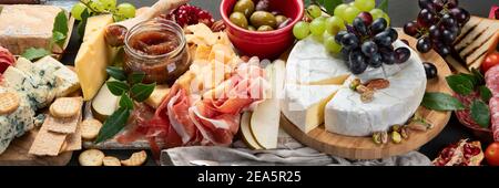 Tavola degli antipasti. Formaggio, fusit e cartone di carne su sfondo scuro. Banner panorama Foto Stock