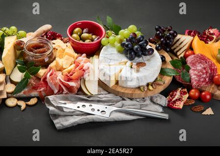 Tavola degli antipasti. Formaggio, fusit e cartone di carne su sfondo scuro Foto Stock