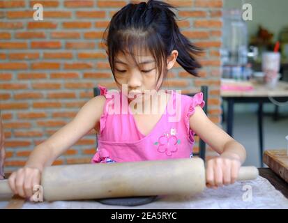 Una giovane ragazza asiatica carina imparando a modellare l'argilla nella sua classe di ceramica, modellando l'argilla in un piatto e decorandola. Foto Stock