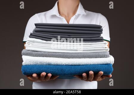 Primo piano di una donna che tiene una pila di asciugamani e lenzuola puliti. Foto Stock