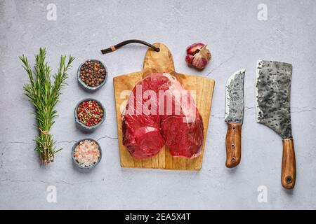 Vista dall'alto del prosciutto crudo di cervo fresco disossato con spezie e erba su sfondo concreto Foto Stock