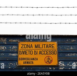 Area militare italiana con segno giallo: 'Zona sanitaria, senza ingresso, sorveglianza armata'. 'Zona militare, divito di accesso, sorvoglianza armata' Foto Stock